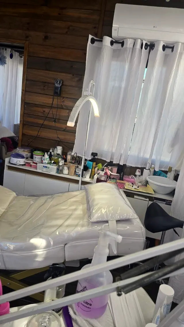 Estação de trabalho com maca, luminária e materiais no Studio Sandra Araújo